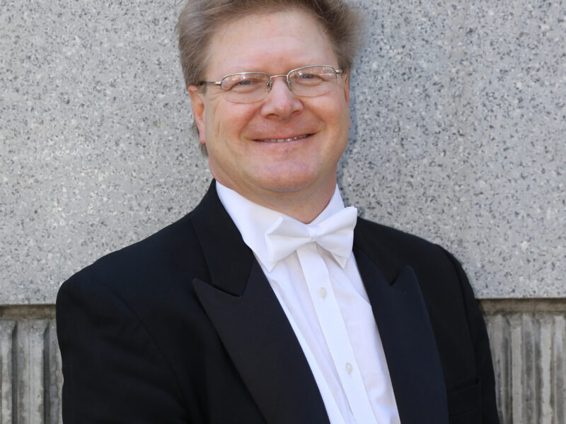 a man in a tuxedo smiles at the camera