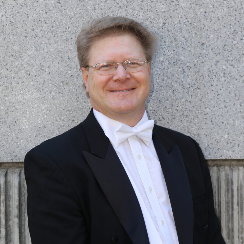 a man in a tuxedo smiles at the camera