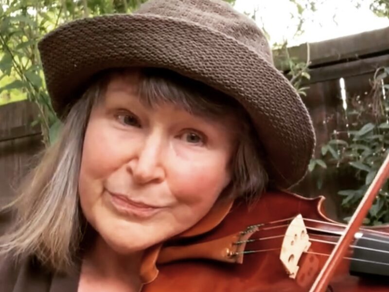 a woman wearing a hat holding a violin under her chin